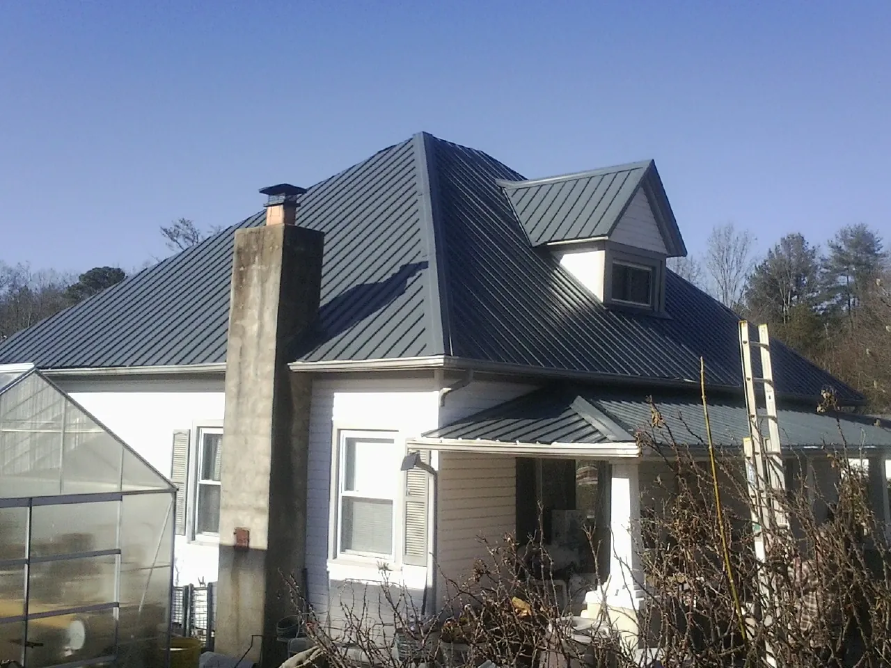 Dark blue standing seam metal roof on a white farmhouse with dormer — Slate & Tile Roof Repair by Roofing Brothers in Reseda