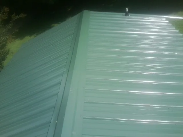 New green metal panels meeting at the ridge of a roof — Flat Roof Repair work by our crew in Reseda