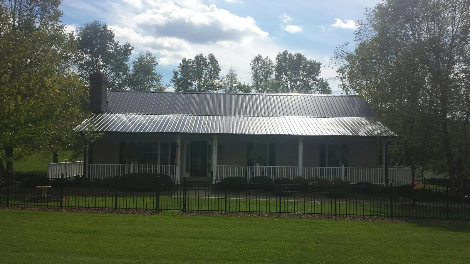 Gray metal roof on a brick ranch with a full width front porch — Gutter Guard Installation work by our crew in Reseda